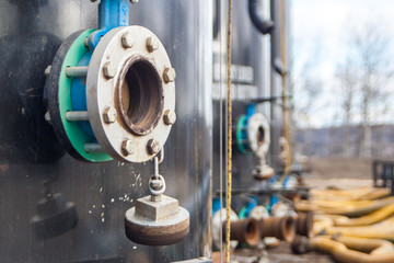 A close up of a connection hatch on a barrel at a drilling  well site.