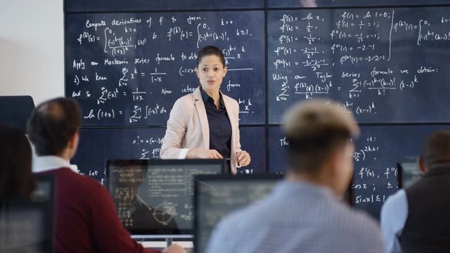 Teacher in adult education class explaining math formulas to students