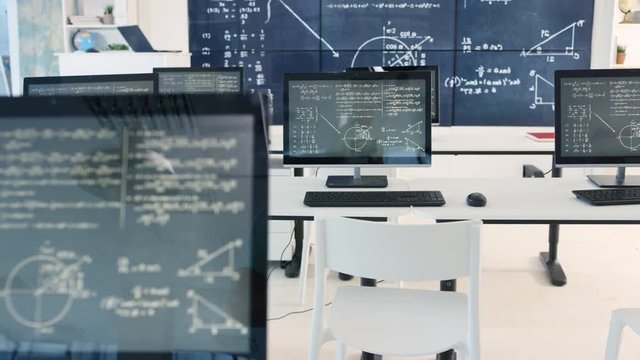  Interior of empty classroom with computers & math formulas on blackboard