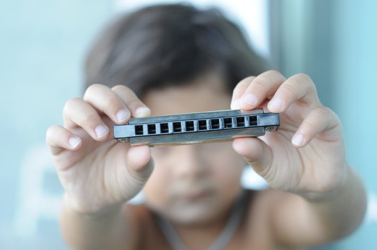 Child unfocused holding a harmonica in the foreground
