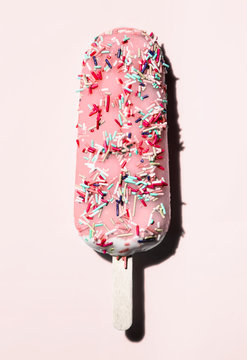 pink popsicle with sprinkles on pink background