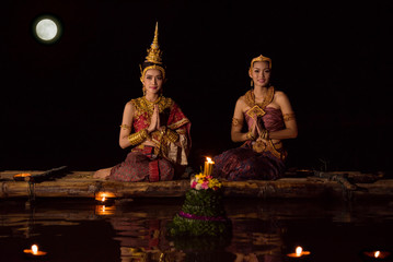Beautiful asian women in traditional Thai dress sitting on floating raft in Loy krathong festival