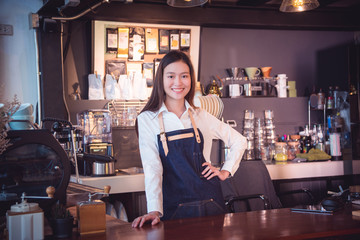 Beautiful asian barista standing and smiles in her cafe