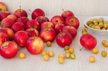 There are lot of red apples and green berries on table