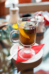 glass of tea with lemon, cinnamon sticks, anise star and mint  mint leaves on table in cafe
