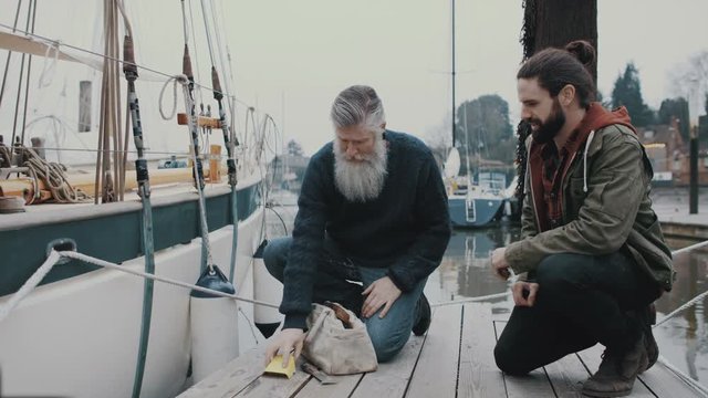 Father and son with sailing boat walking along the jetty in a marina