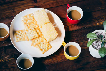  four cups of coffee  and  biscuits in the plate  on brown wood table.