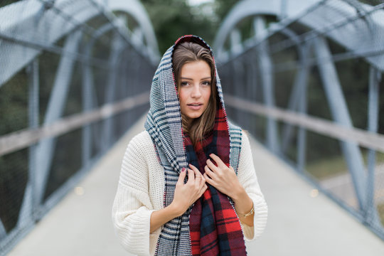 Beautiful woman with a scarf wrapped around her head standing on a bridge