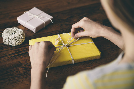 Over the shoulder of woman wrapping gifts