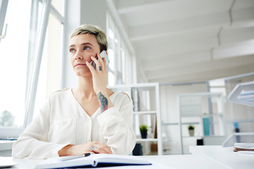 Busy employee speaking by smartphone while planning work or making research