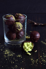 Healthy raw energy bites with coconut, avocado and tea matcha. Vegan chocolate truffles on dark wooden background. Homemade candy. Copy space