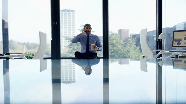  Cheerful businessman talking on phone in front of window in his office