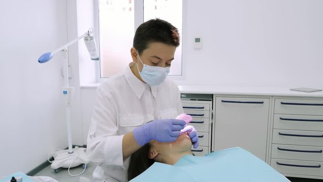 The dentist puts the mouth expander for a beautiful girl in the dental office.