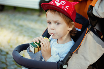 Little boy drinking juice on the street.