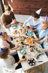 Several friends in birthday caps having festive food by table