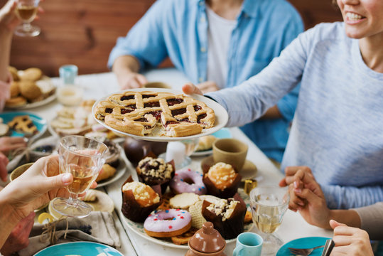 Woman offering tasty sweet pie with jam to one of guests by festive tavle