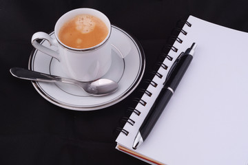 A cup of coffee with a notepad.
