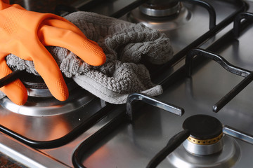 Close up view of hands in rubber gloves cleaning hob
