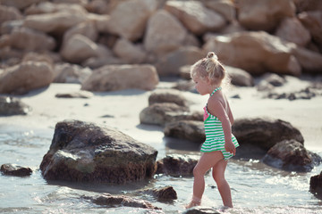 Little cute happy girl bathes in sea,