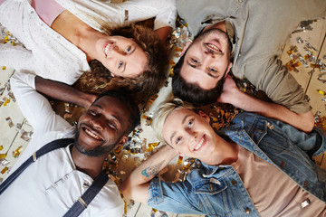 Four young companions lying on the floor with hands behind heads