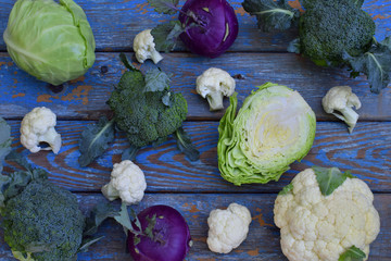 Obraz premium Composition from different varieties of cabbage on wooden background. Cauliflower, kohlrabi, broccoli, white head cabbage. Organic fresh vegetables