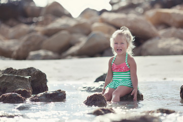 Little cute happy girl bathes in sea,