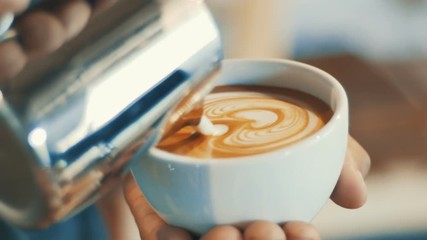 barista pouring streamed milk to make heart shape latte art in cup of hot coffee, retro tone