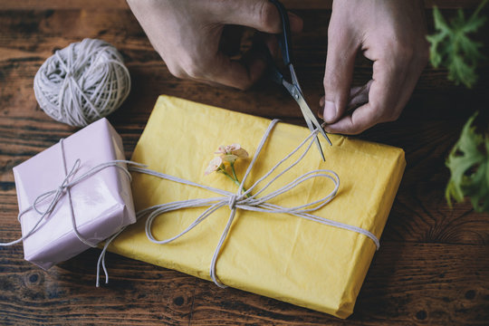 Man_??s hands cutting twine tied around a gift