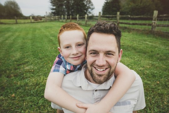 Playful father smiling with young son in farm field