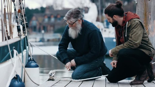  Father & son fishermen chatting on the jetty while mooring their boat