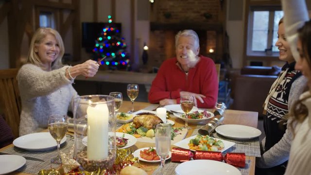 Happy family together at Christmas, pulling crackers at the dinner table