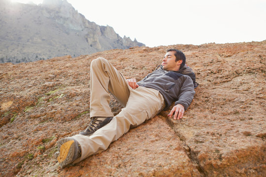 Young man rests on rock cliff