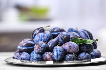 Plate with tasty ripe plums on table