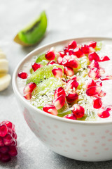 Winter fruit kiwi pomegranate banana breakfast smoothie bowl. Selective focus, copy space, close up.