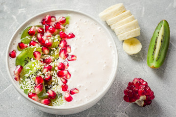 Healthy kiwi pomegranate banana greek yogurt smoothie bowl. Selective focus, copy space.
