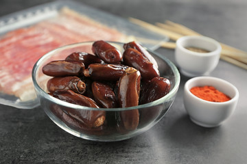 Bowls with ripe dates and spices on grey background
