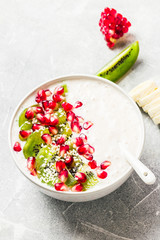 Winter fruit smoothie bowl with kiwi pomegranate banana yogurt.  Selective focus, copy space, close up.