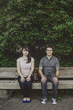Young stylish couple with dachshund  dog looking serious outside - portrait on bench