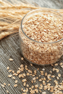 Glass jar with oatmeal flakes on wooden background
