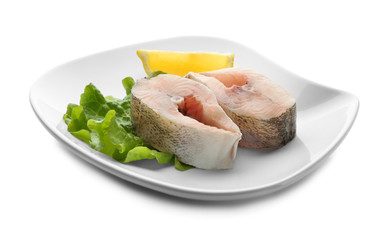 Plate with fresh fish steaks on white background