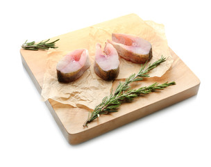 Wooden board with fresh fish steaks on white background