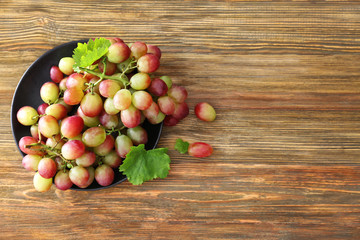 Plate with fresh ripe grapes on wooden background