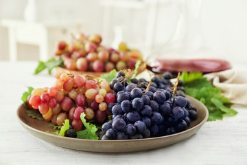 Plate with fresh ripe grapes on table