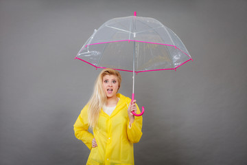 Woman holding transparent umbrella looking shocked
