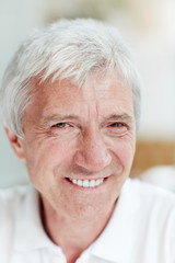 Senior grey-haired man with toothy smile looking at camera