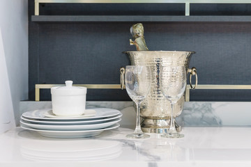 modern kitchen counter with bottles of Champagne in cooler, kitchenware on a white granite worktop