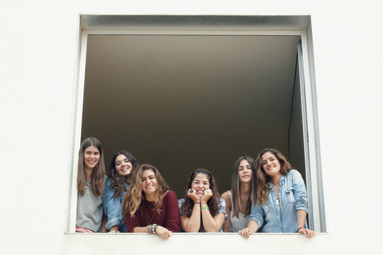 Group of six girls looking from up on a window