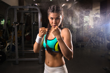 Fototapeta na wymiar Brave sporty girl showing her fists during workout in gym