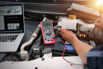 Close up of auto mechanic jumping battery car,check voltage level car battery,helping concept.