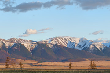 panoramic view of plain at root of great mountains with snowy tops 
